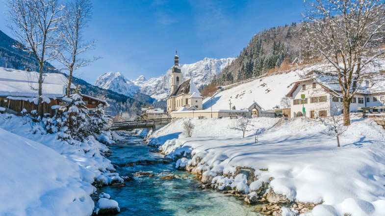 Panoramic view of scenic snowy landscape in the Bavarian Alps with famous Parish Church during winter in Germany.