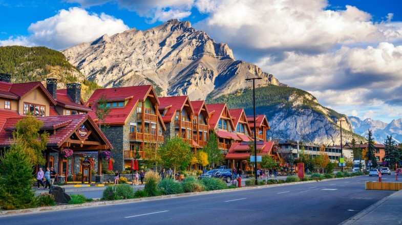 Scenic street view of Banff Avenue with cars and tourists in Canada in June.