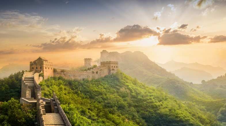 The Great Wall in China in June during sunset, surrounded by greenery.