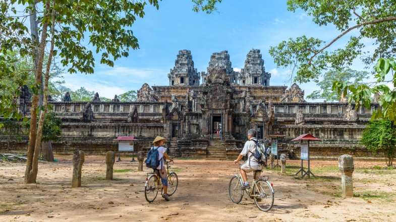 Couple cycling around Angkor Watt during a clear day in Cambodia in November.