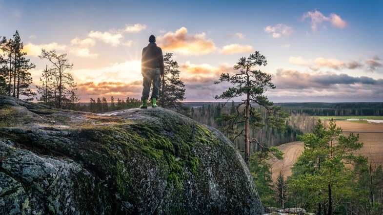 Hiker enjoying the view of beautiful landscape from top in Finland in May.