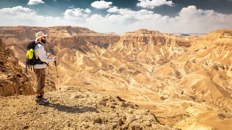 A young hiker on mountain ridge cliff edge in Israel in September.
