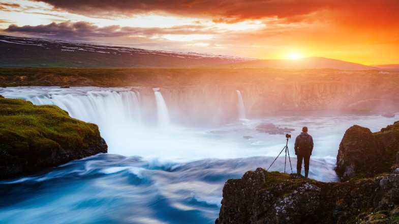 Man clicking Godafoss waterfall; one of the things to do in Iceland.