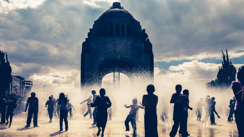 Kids play in the fountains in the center of city in Mexico in June.