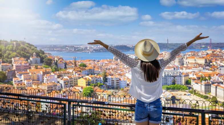 A happy tourist looks at the colorful town of Lisbon, one of the best places to visit in Portugal.