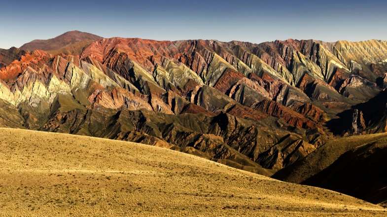 The mountains of Quebrada de Humahuaca flaunt waves of colors, ranging from rich bands of red, vibrant pink, creamy white, and patches of green.