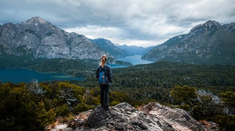 A woman stands and enjoys the valley viewpoint from the top, things to do in Bariloche.