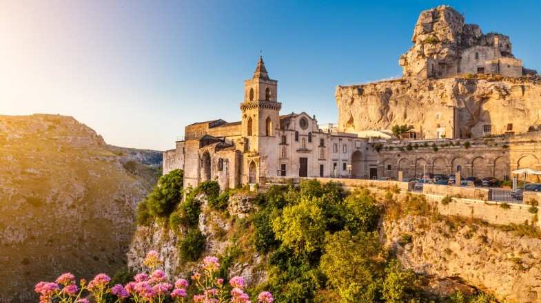 The rocky cliff-side of Matera is clustered with old houses perched on top.
