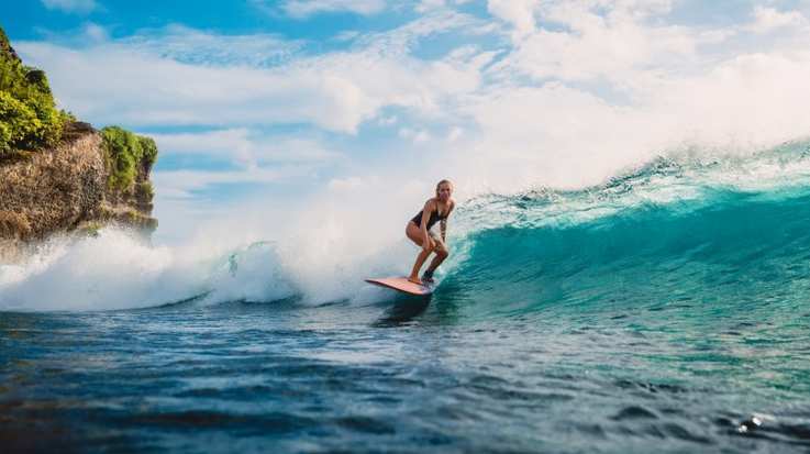 A woman surfing on a board in the beach of Australia in September.