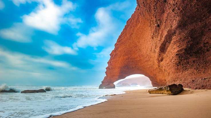Red arch of Legzira beach during summer in Morocco.