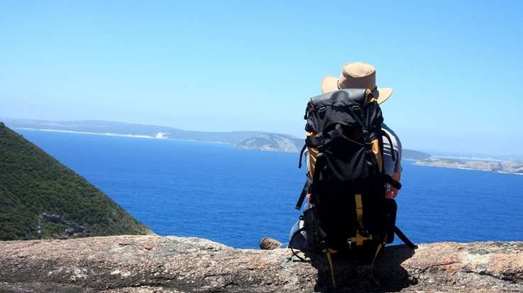 A man rests after hiking over a scenic landscape in Australia.