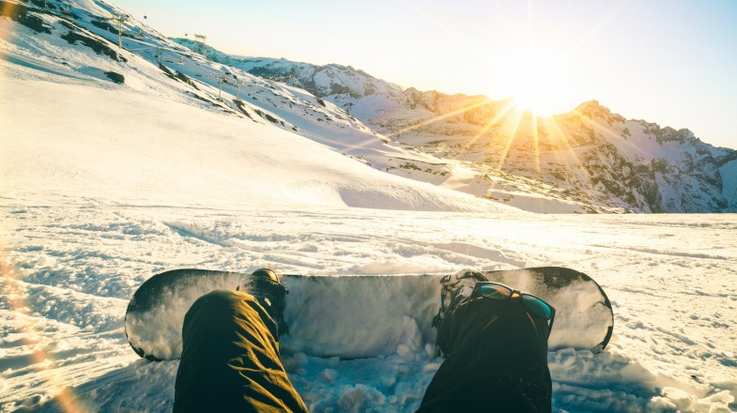 Snowboarder sitting and enjoying the sunset in Italy in January.