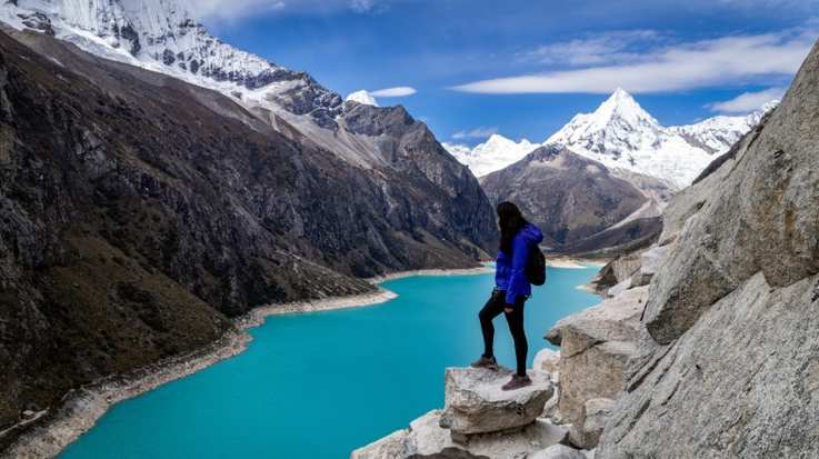 Woman standing at a cliff above Lake Paron during winter in Peru.