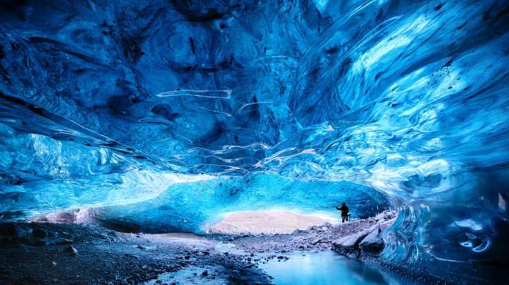 Man admiring an ice cave within Breioarmerkurjokull, Iceland, in November.