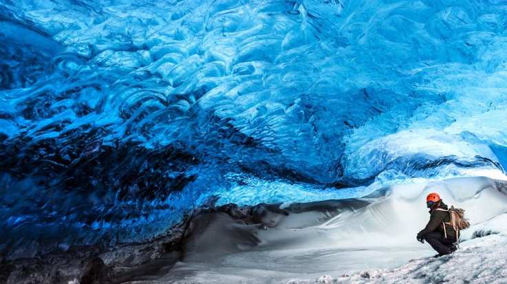 Traveler sitting in the ice cave near Skaftafell glacier.