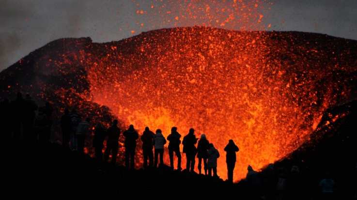 A group of visitors witnesses a volcano eruption