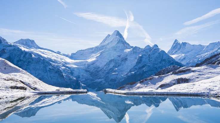 The Alps reflected in Bachalsee Lake during winter in Switzerland.