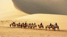 Tourists riding camels in the desert during their journey on Silk Road in China