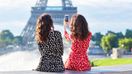 Beautiful sisters photographing the Eiffel Tower while traveling in Paris