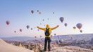 A man with open arms in Cappadocia looking at hot-air balloons while spending 10 days in Turkey.