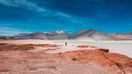A person stands next to a water body in the arid landscape of Atacama during a trip for one week in Chile.