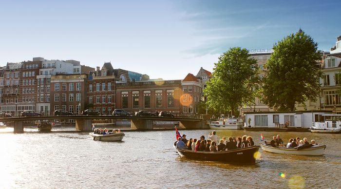 People having boat rides on one of the canals of Amsterdam. Amsterdam is known for having one hundred kilometres of canals, about 90 islands and 1,500 bridges.