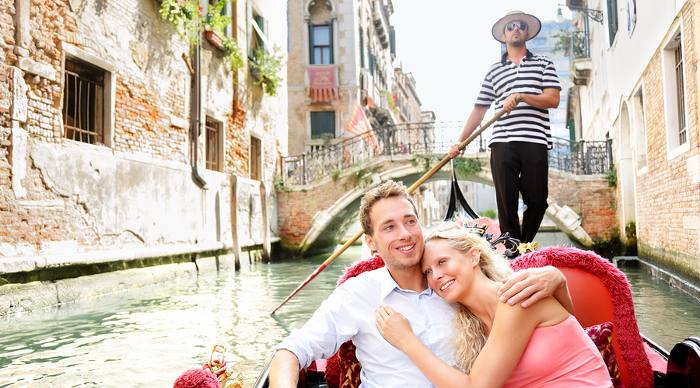 Romantic travel couple in Venice on Gondola ride, happy together on travel vacation holidays. 