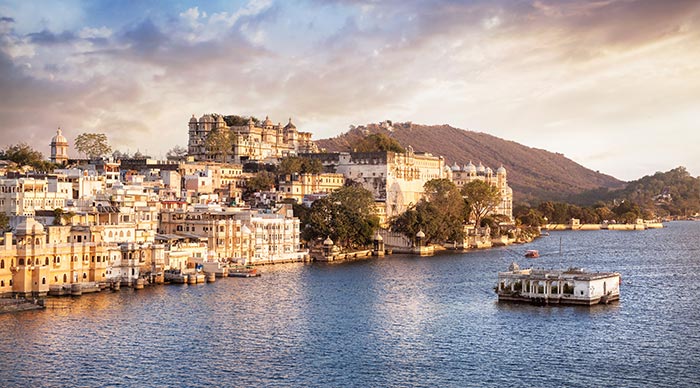 Lake Pichola with City Palace view at cloudy sunset sky in Udaipur Rajasthan India