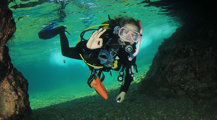 Young Woman scuba diving into the cave in Italy
