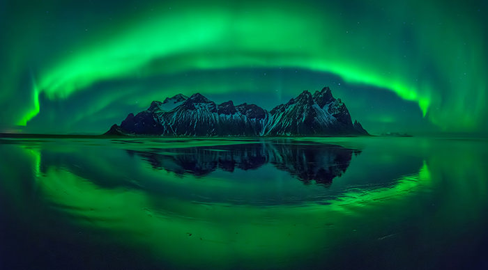 Aurora reflections on Stokksnes black beach with Vestrahorn mountains in center Iceland